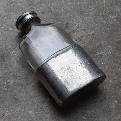 an old metal flask sitting on the ground next to it's capping