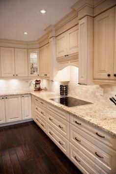 a kitchen with white cabinets and wood floors