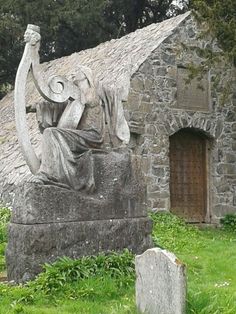 an old stone building with a statue in front of it and a woman holding a harp