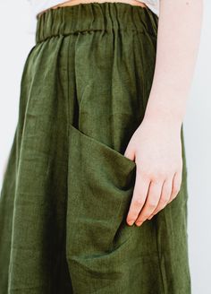 a person with their hand in the pocket of a green pants that is rolled up