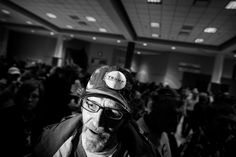 a man wearing a hard hat and glasses in front of a large group of people