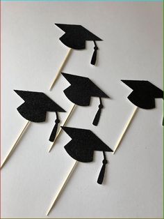 black graduation hats and tassels on top of toothpicks in front of a white background