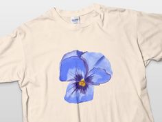 a white t - shirt with a blue flower painted on it