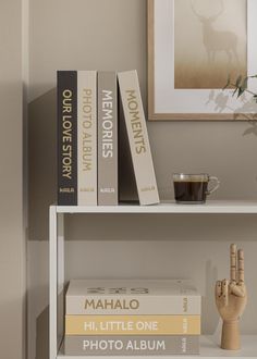 two books on a shelf next to a vase with flowers and a small wooden hand