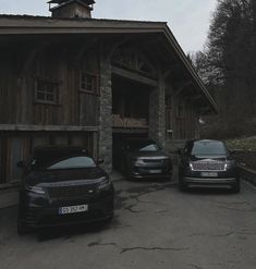 two black cars parked in front of a wooden building with a steeple on top