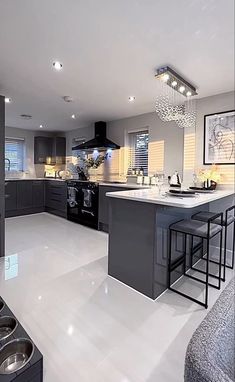 a modern kitchen with an island and bar stools in the center, surrounded by gray cabinets