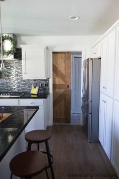 a kitchen with two stools in front of the counter top and an open door