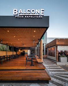 a restaurant with wooden tables and benches on the outside patio area that has balcone pizza napolita written on it