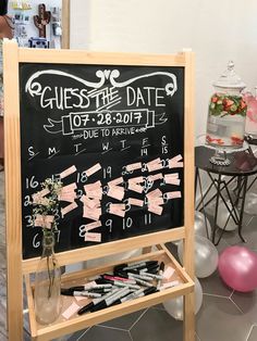 a blackboard with pink bows on it in front of balloons and other items for sale