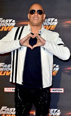 the rock is making a heart shape with his hands while posing in front of a black and white backdrop