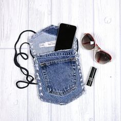 a cell phone in a pocket next to sunglasses and keys on a white wooden floor