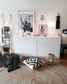 a white dresser sitting next to a black and white rug on top of a wooden floor