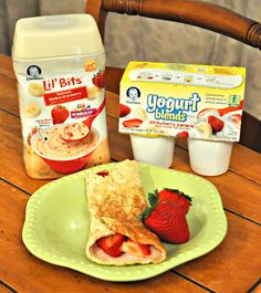 a green plate topped with food next to yogurt cups and a container of fruit