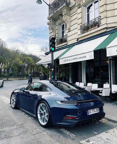 a blue sports car parked in front of a building on a street corner next to a green traffic light