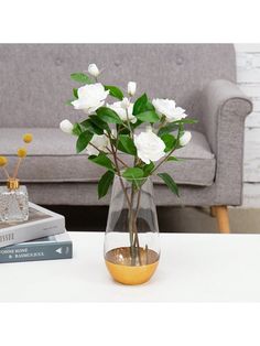 a vase filled with white flowers sitting on top of a table next to a couch