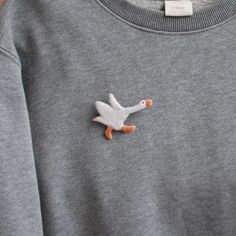 a gray sweater with a white duck embroidered on it