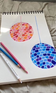 an open notebook with two different colored circles on it next to pencils and markers