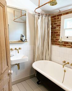 a white bath tub sitting under a bathroom mirror next to a sink and a window