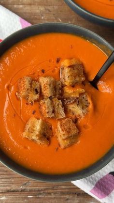 two bowls of tomato soup with croutons on top