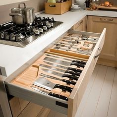 an open drawer in the middle of a kitchen with utensils and other items