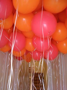 orange and pink balloons are hanging from the ceiling