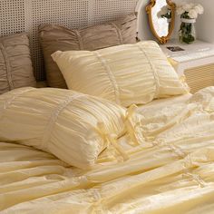 an unmade bed with yellow comforter and pillows on it in front of a mirror