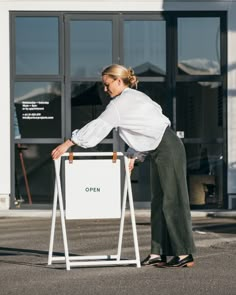 a woman leaning on a sign in front of a building