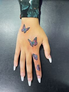 a woman's hand with tattoos on it and three butterflies tattooed on the wrist