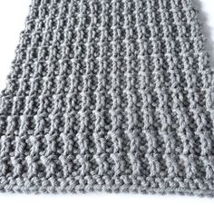 a gray knitted blanket laying on top of a white floor