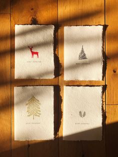 four pieces of paper with designs on them sitting on a wooden floor next to a window