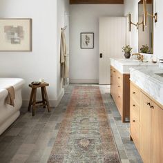 a bathroom that has a rug on the floor in front of it and a bathtub next to it