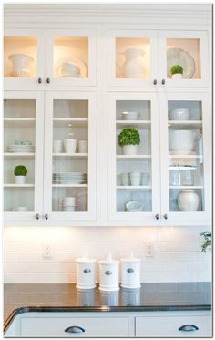 a kitchen with white cabinets and glass front cabinets