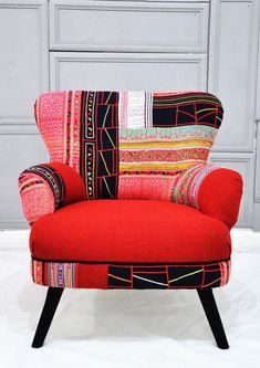 a red chair sitting on top of a white floor next to a wooden frame wall