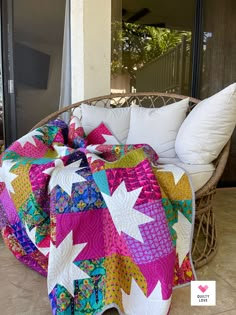 a colorful quilt sitting on top of a wicker chair next to a white pillow