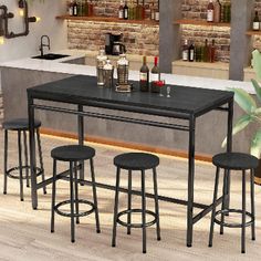 a kitchen table with four stools next to an island and bar in the background