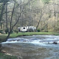 an rv parked on the side of a river next to a camping area with a camper