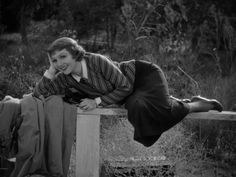 a woman laying on top of a wooden bench