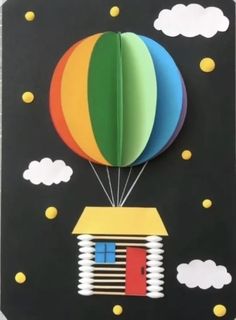 an origami hot air balloon with a house on the roof and clouds in the background