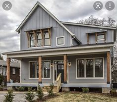 a gray house with two story windows and wood trimmings on the front porch