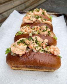 several hot dogs on buns with shrimp and garnishes are ready to be eaten