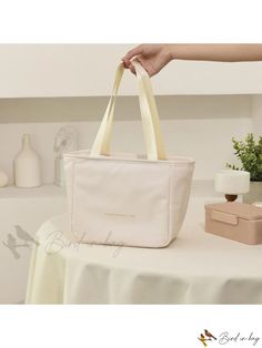 a white bag sitting on top of a table next to a vase and candle holder