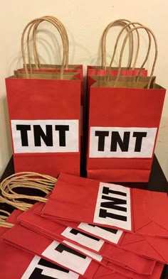 two red bags with white and black letters on them sitting on a table next to twine