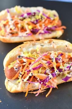 two hotdogs with coleslaw and carrot slaw are on a baking sheet