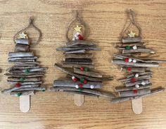 three small christmas trees made out of driftwood on popsicle sticks with red, green and white decorations