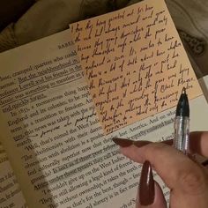 a person holding a pen and writing on top of an open book with letters written in cursive writing