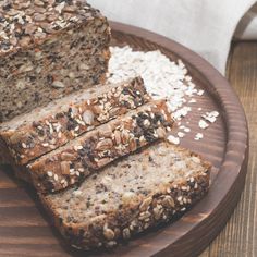 sliced loaf of bread sitting on top of a wooden plate next to oatmeal