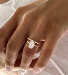 a woman's hand with a diamond ring on her left hand and the other hand holding an engagement ring