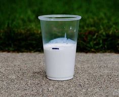 a glass filled with milk sitting on the ground