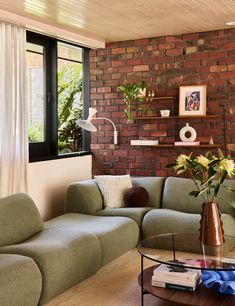 a living room filled with furniture and a brick wall behind the couch is a coffee table