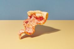 a half eaten piece of pizza sitting on top of a yellow countertop next to a blue wall